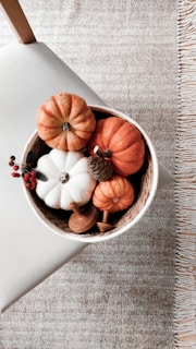 a bowl filled with fake pumpkins on top of a table