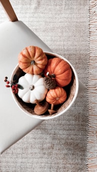 a bowl filled with fake pumpkins on top of a table