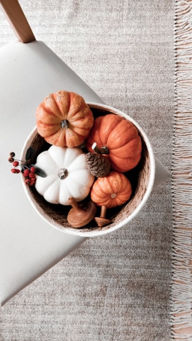 a bowl filled with fake pumpkins on top of a table