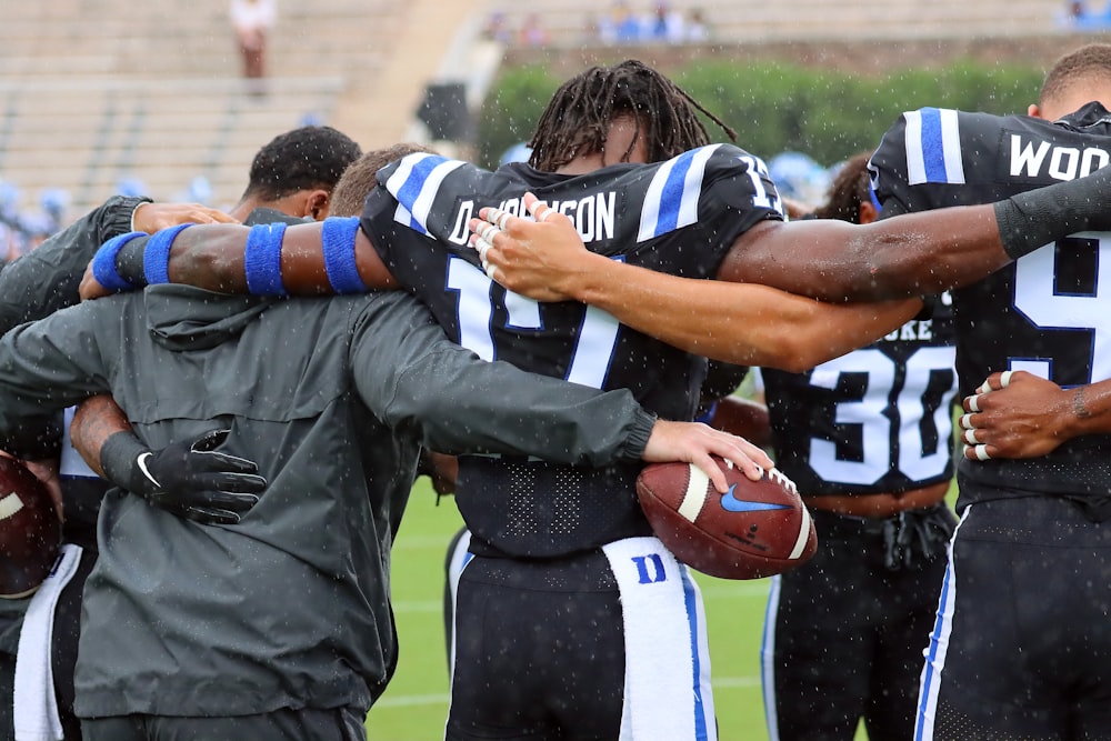 a group of football players huddle together on the field