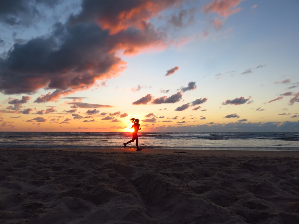 a person running on a beach at sunset