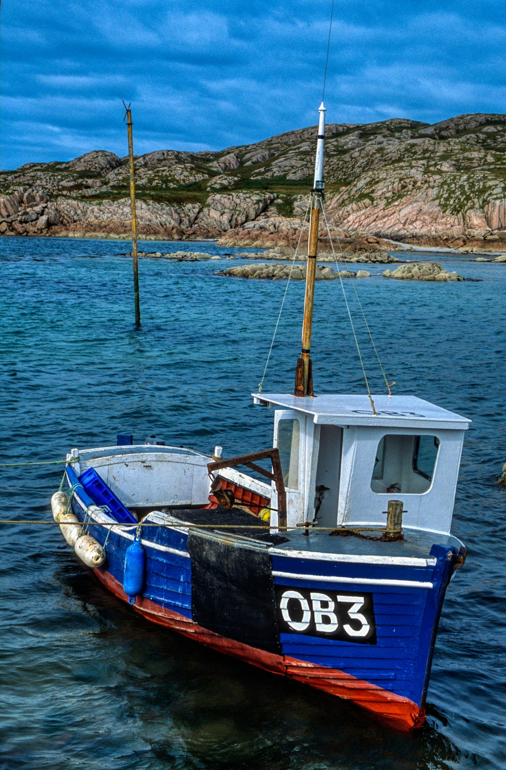 a blue and white boat floating on top of a body of water