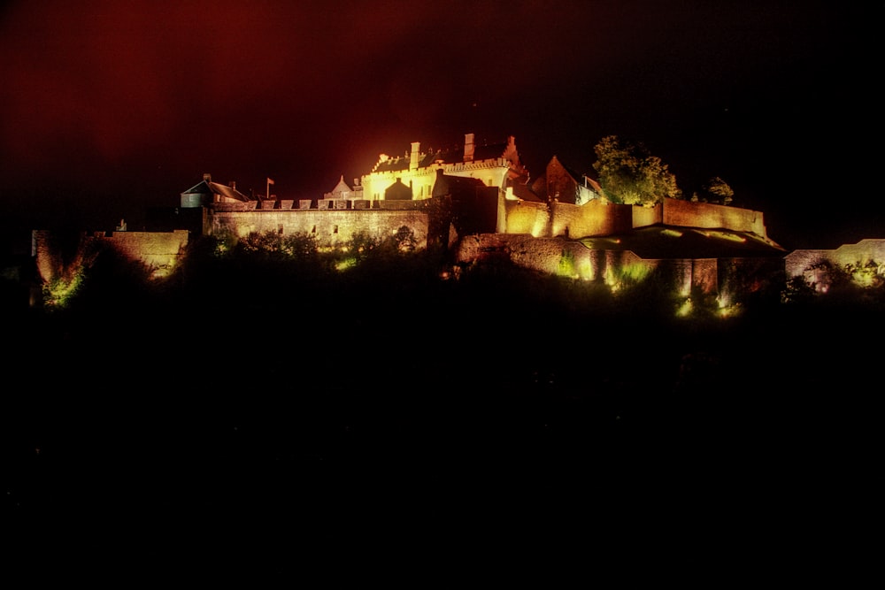 a castle lit up at night with a red sky