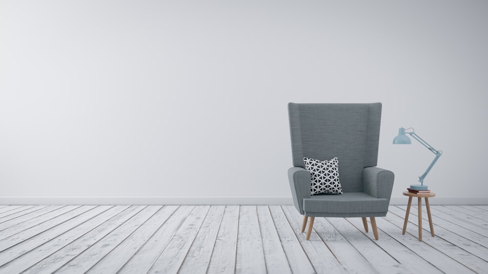 a chair with a pillow and a lamp on a wooden floor