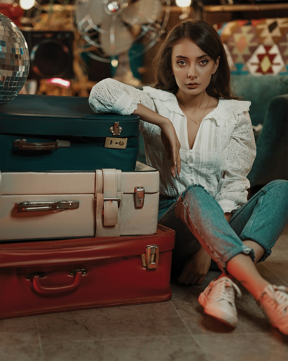 a woman sitting on the floor next to a pile of suitcases