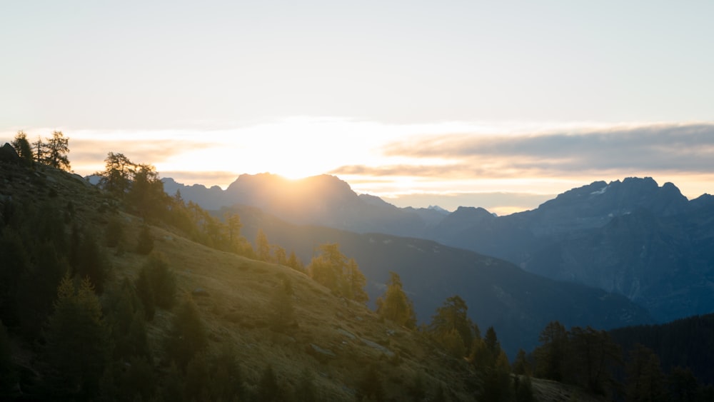 the sun is setting over the mountains in the distance