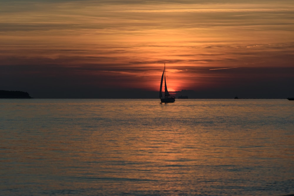 a sailboat in the ocean at sunset