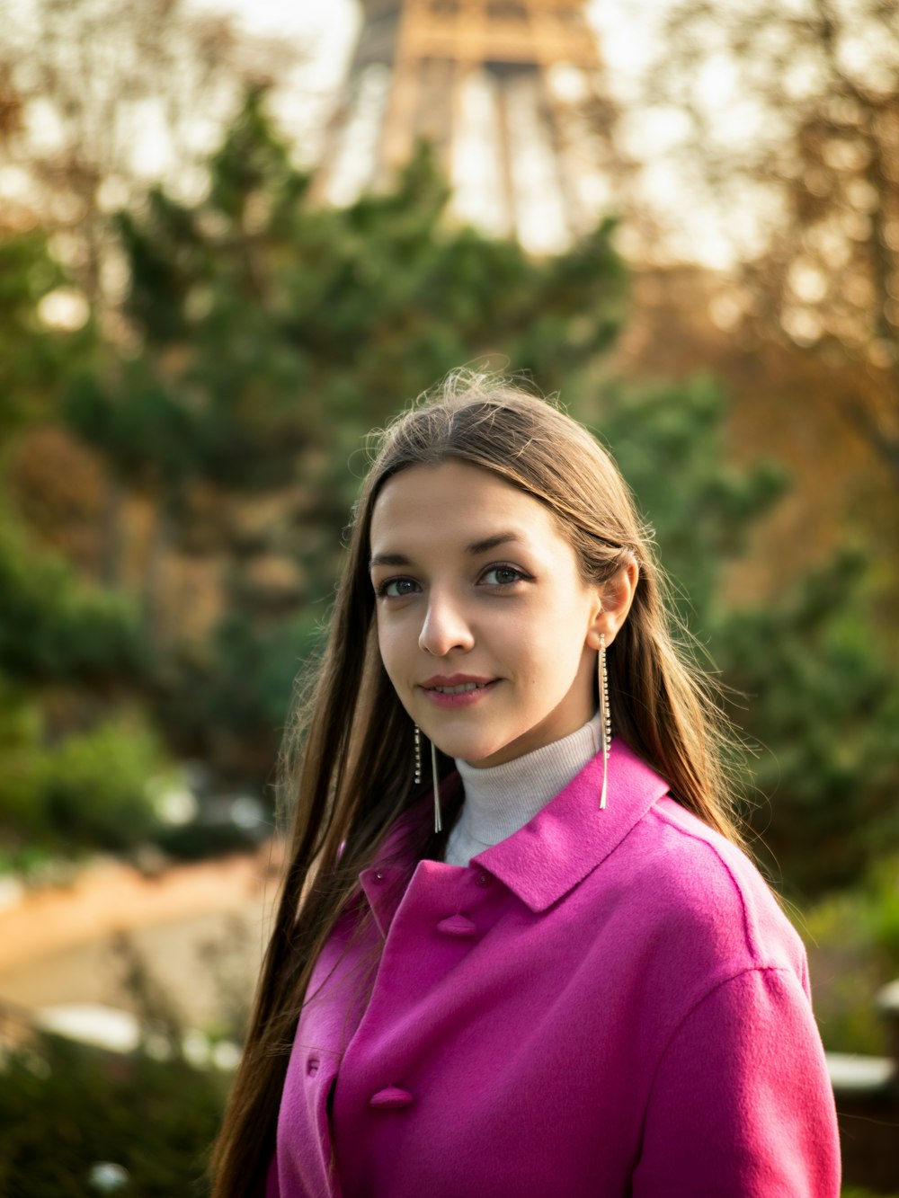 a woman in a pink coat standing in front of the eiffel tower