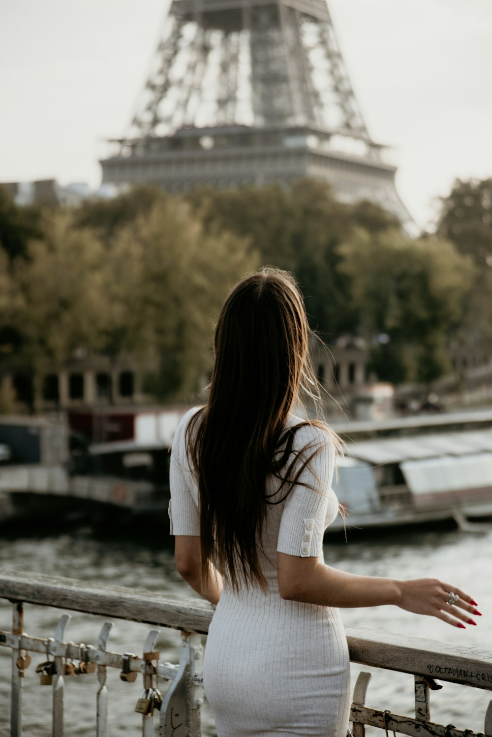 a woman in a white dress looking at the eiffel tower