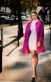 Model walking confidently in pelmora outerwear on a sunlit street.