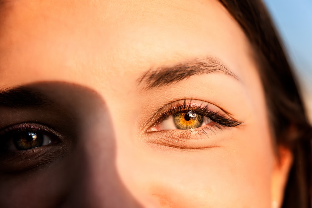 a close up of a woman's eye with a blue sky in the background
