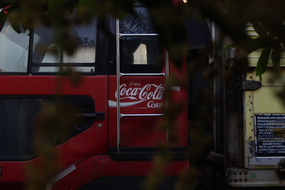 a red bus with a coca cola advertisement on the side of it