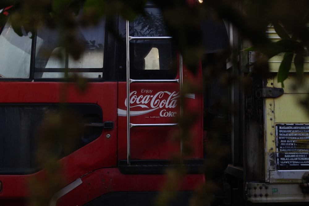 Un autobús rojo con un anuncio de Coca Cola en el costado