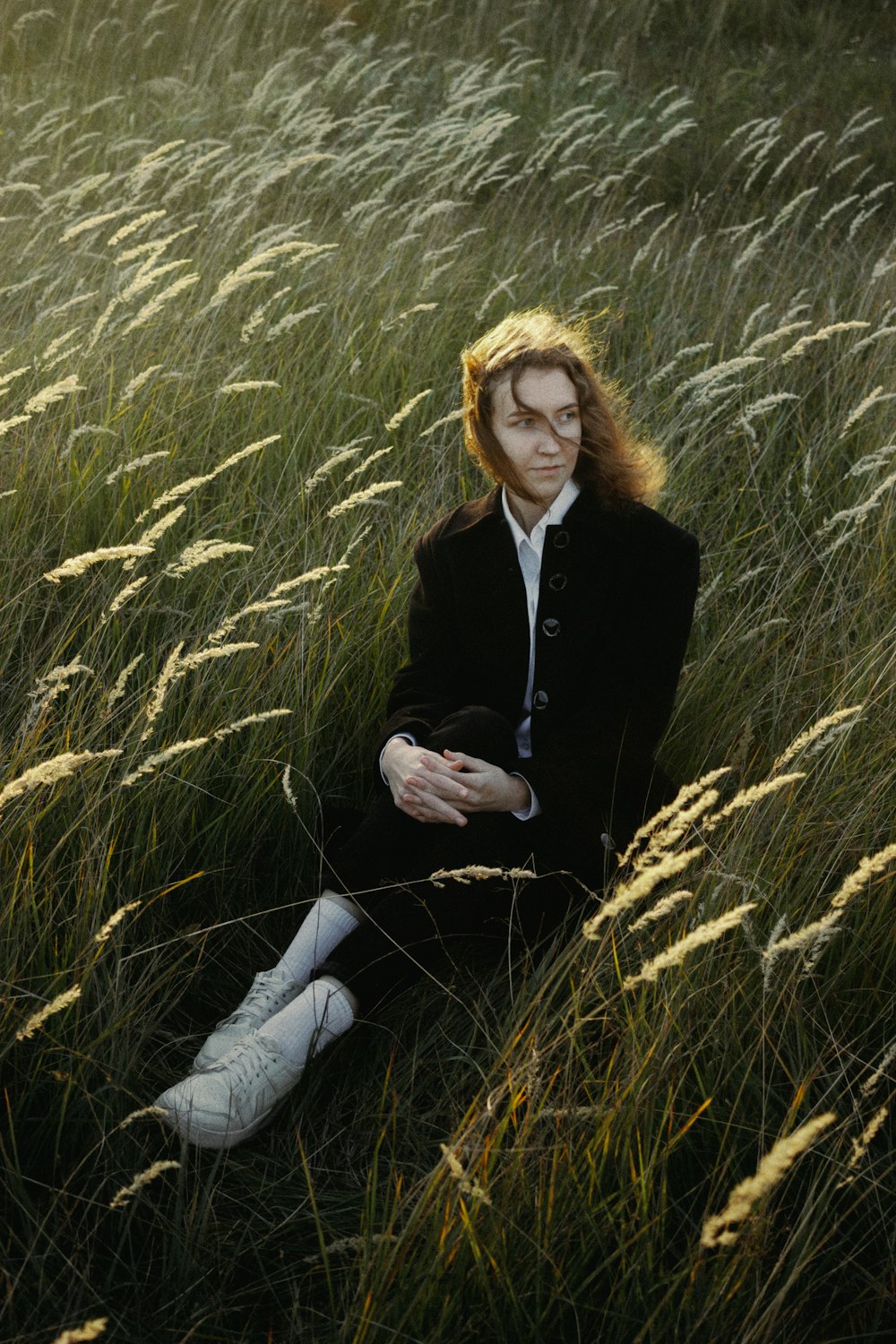 a woman sitting in a field of tall grass