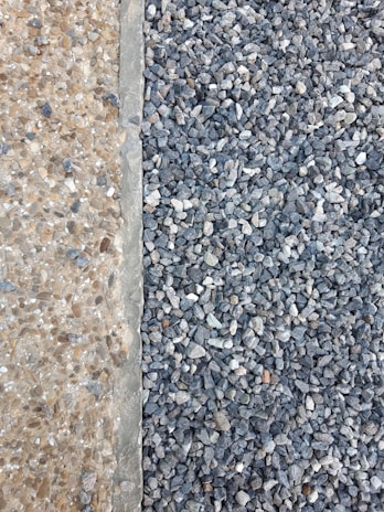 A clear distinction between two types of aggregates is visible. On the left, there are small, beige-colored pebbles mixed with concrete, creating a smooth surface. On the right, larger, gray stones are laid together, forming a textured and rough surface.