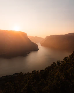 A calm Nordic fjord at sunrise with soft light reflecting on still waters.