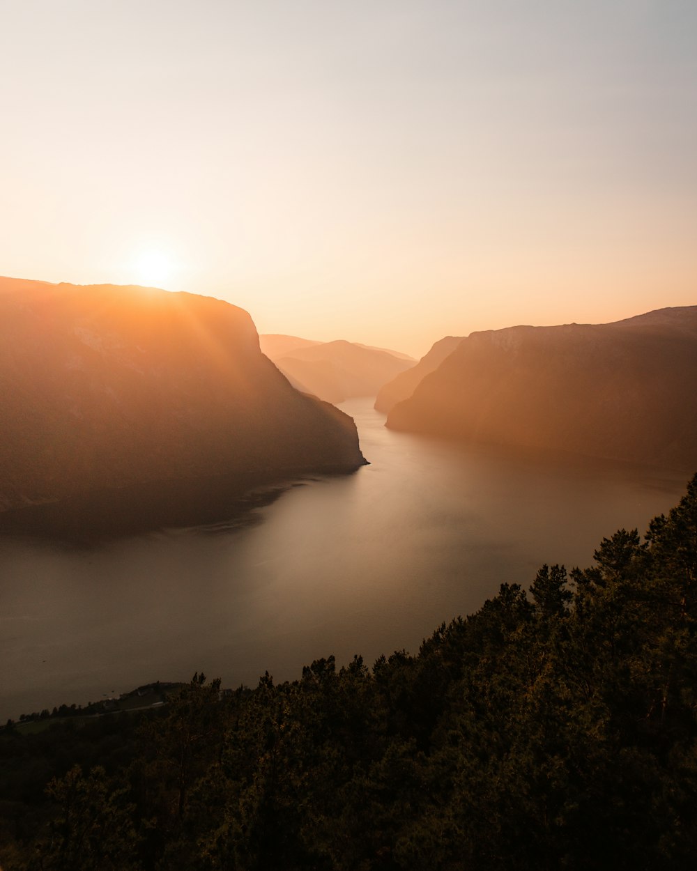 the sun is setting over a lake in the mountains