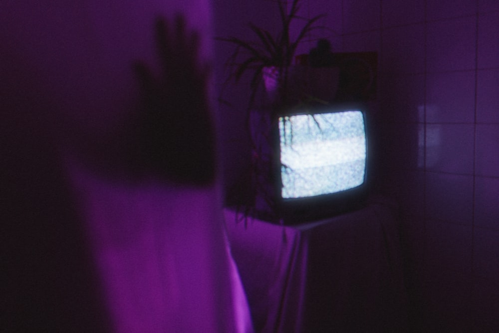 a person standing in a dark room with a tv on