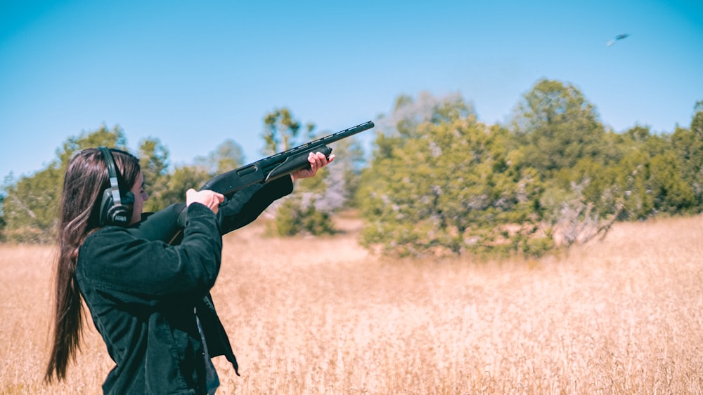 uma mulher segurando uma arma em um campo