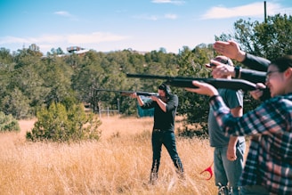 a group of people holding up guns in a field