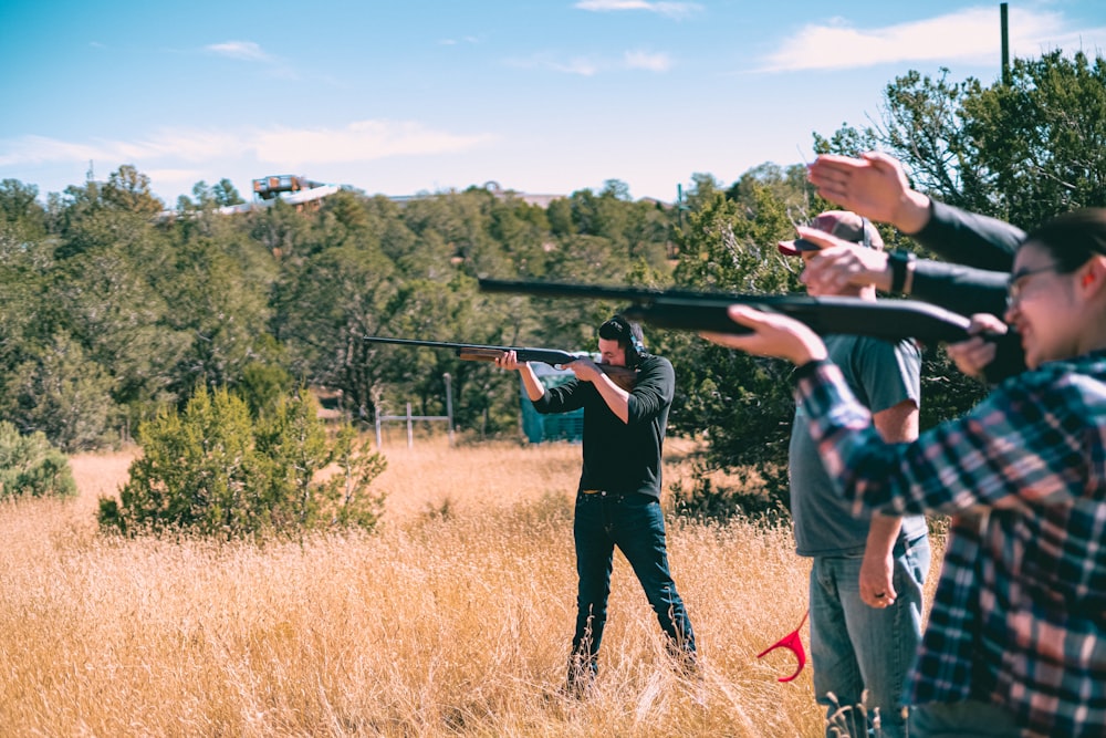 a group of people holding up guns in a field