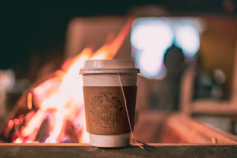 a cup of coffee sitting next to a fire