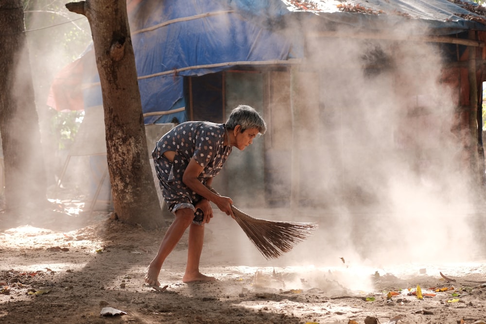a young boy is playing with a broom in the dirt