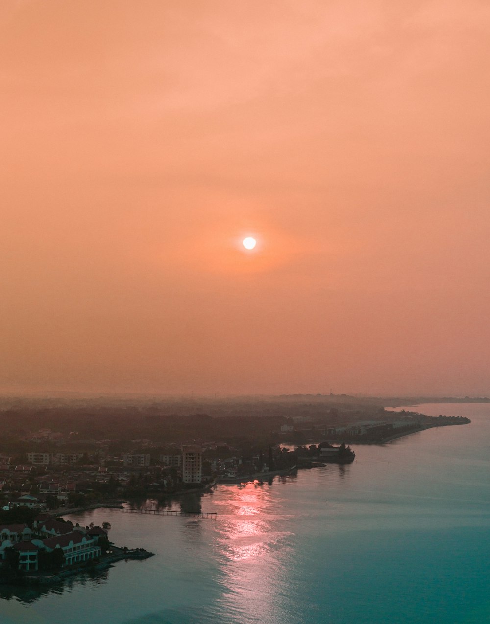 a sunset over a body of water with a city in the distance