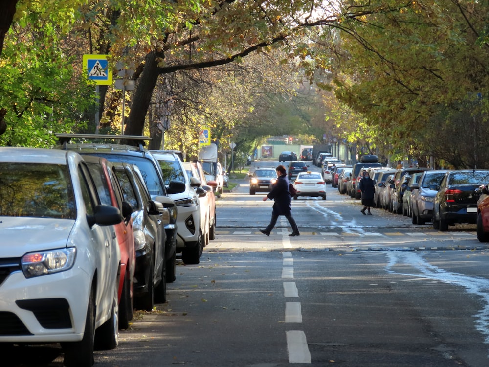 Eine Person, die eine Straße neben geparkten Autos entlang geht