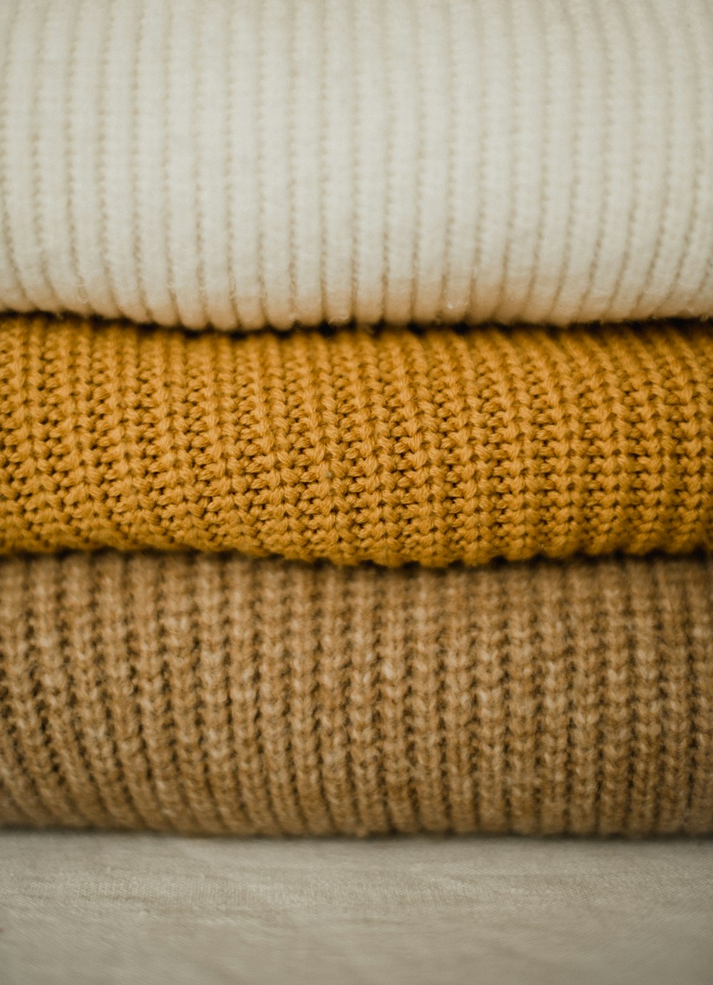 a stack of different colored sweaters sitting on top of each other