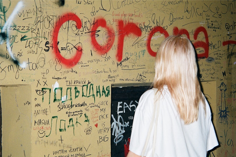 a woman standing in front of a wall covered in graffiti