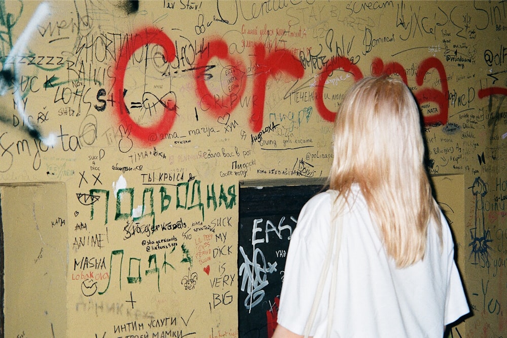 uma mulher em pé na frente de uma parede coberta de grafite