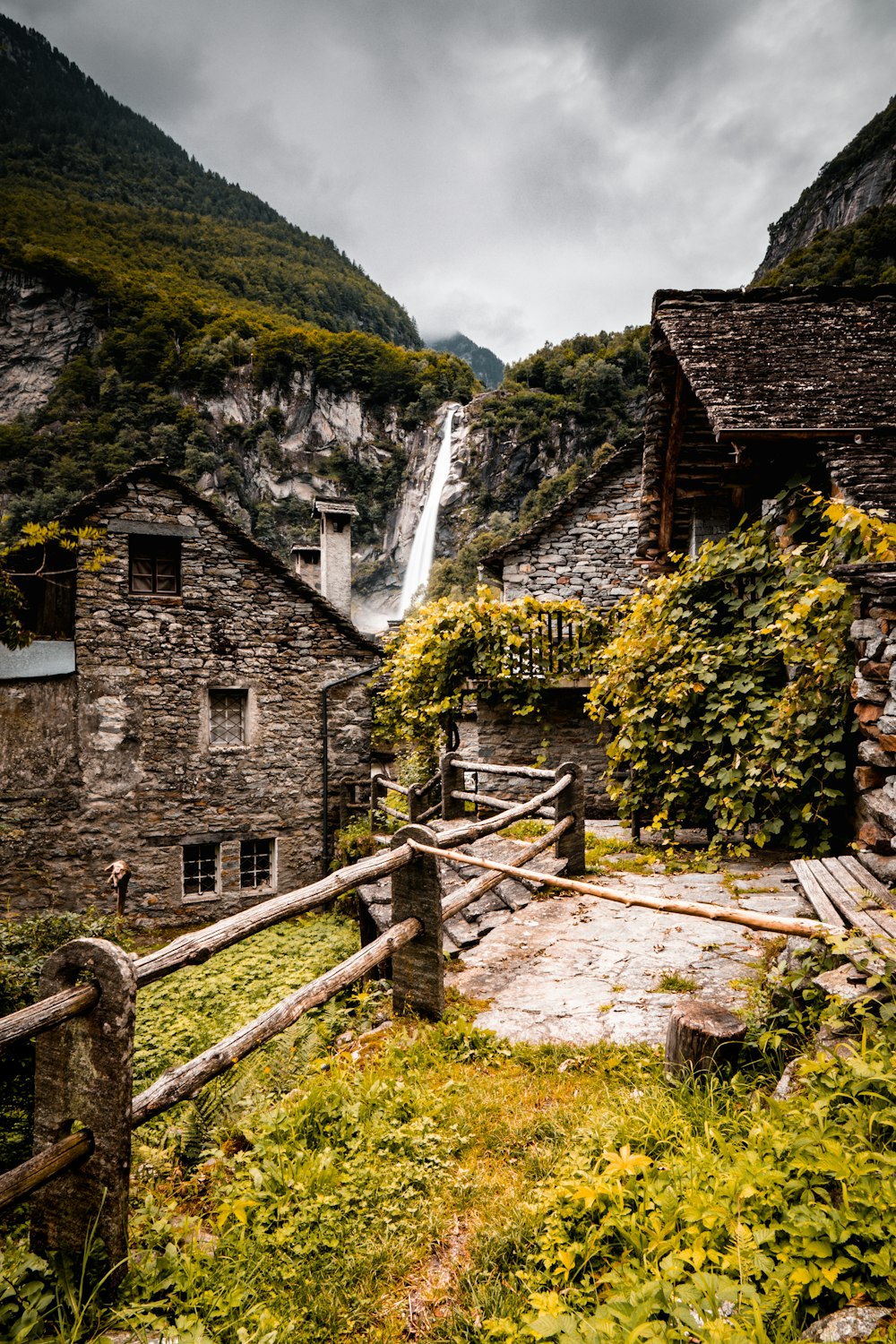 a stone house with a waterfall in the background