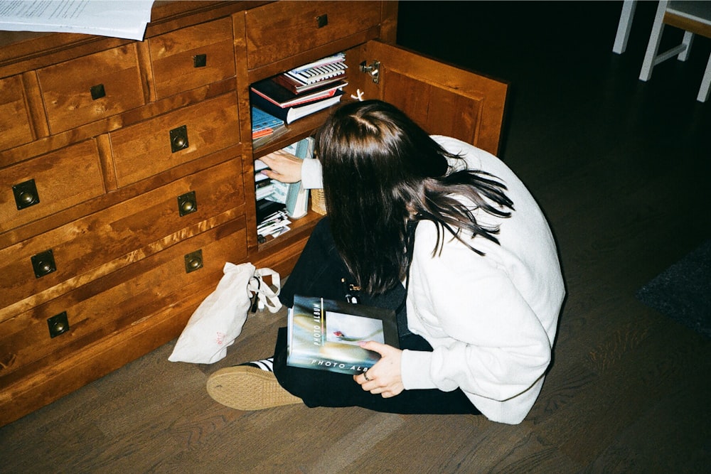 a woman sitting on the floor reading a book