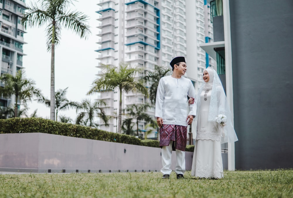 a man and a woman dressed in white standing next to each other