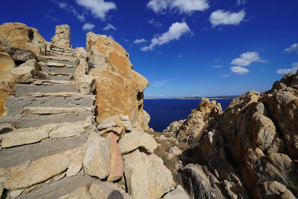 a rocky cliff with stairs leading up to the water