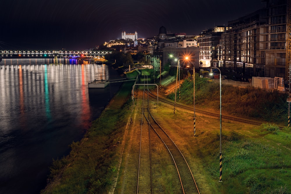 a night view of a train track next to a body of water