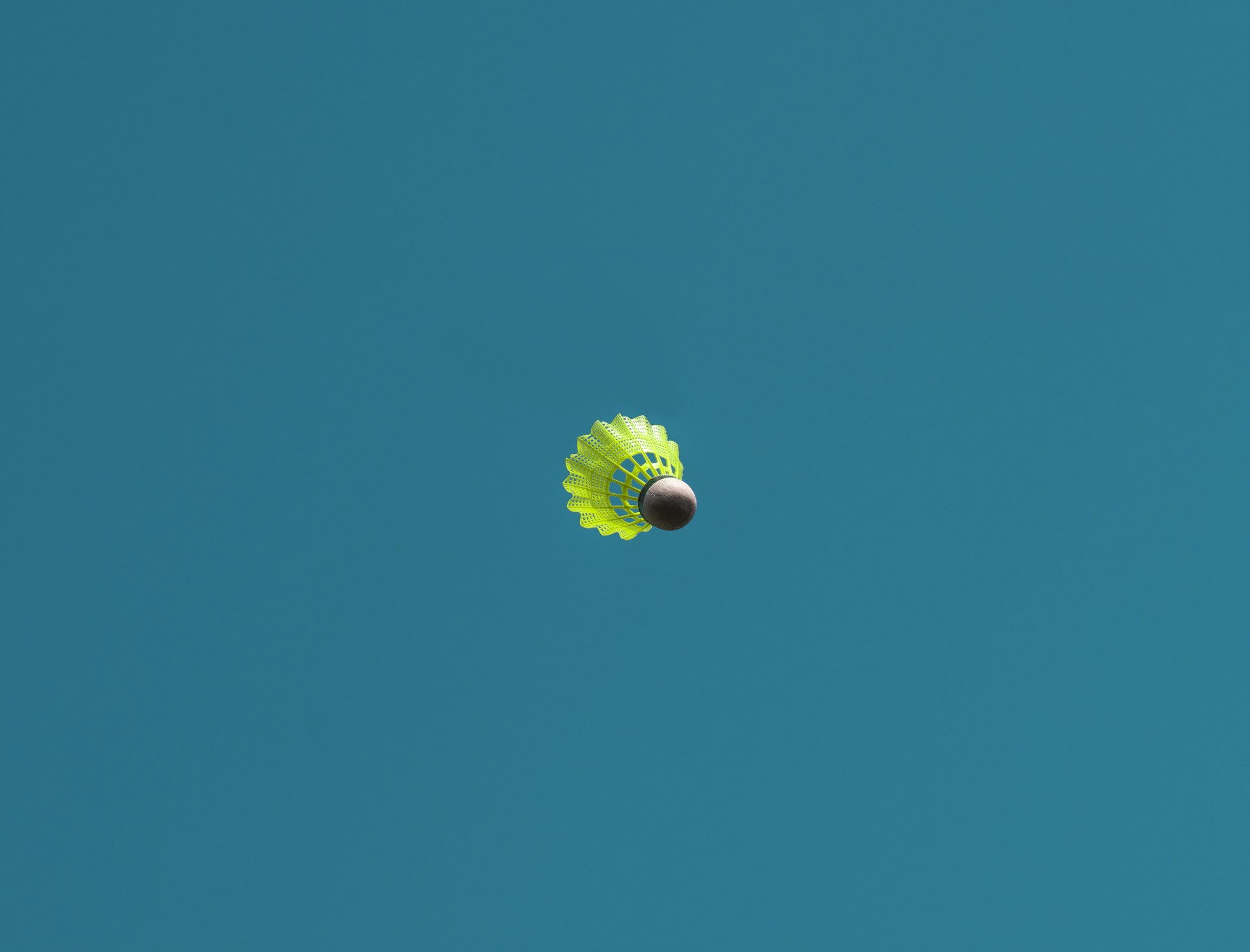 a green and white kite flying in a blue sky