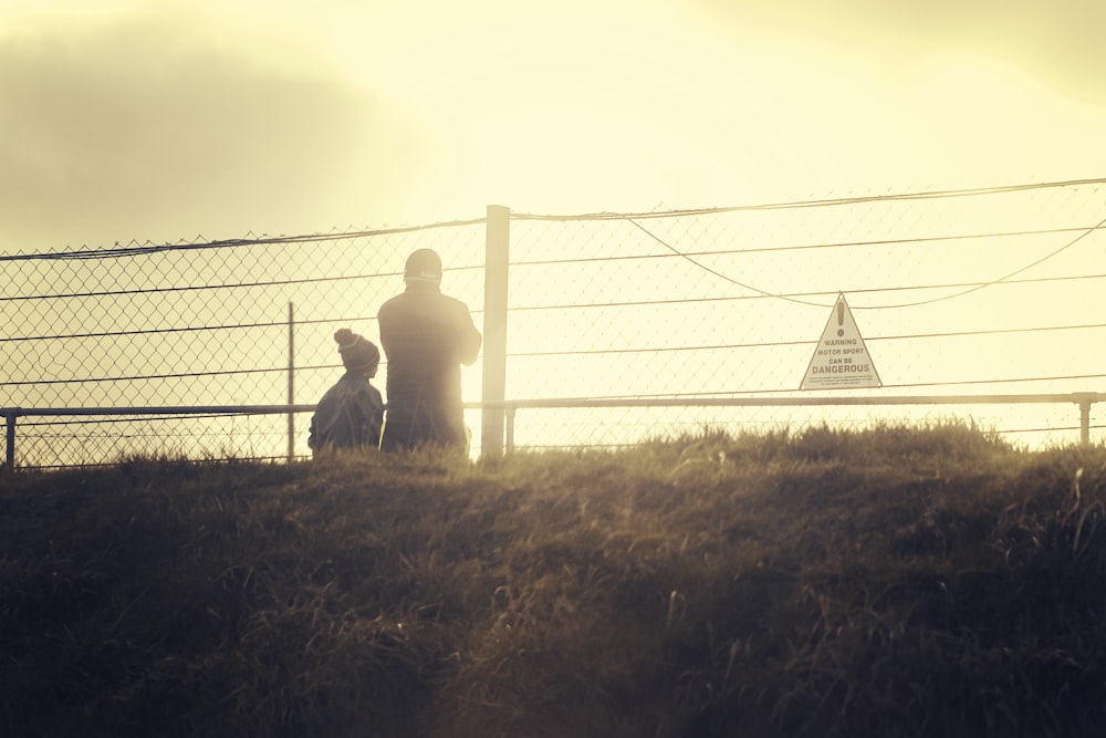 a man and a child standing in front of a fence