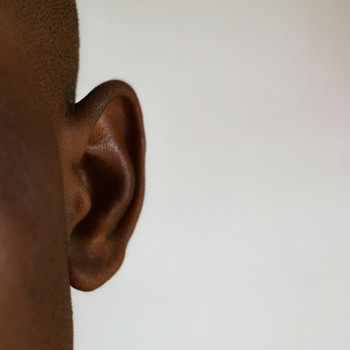 Close-up of a person's ear against a white background, attention to listening