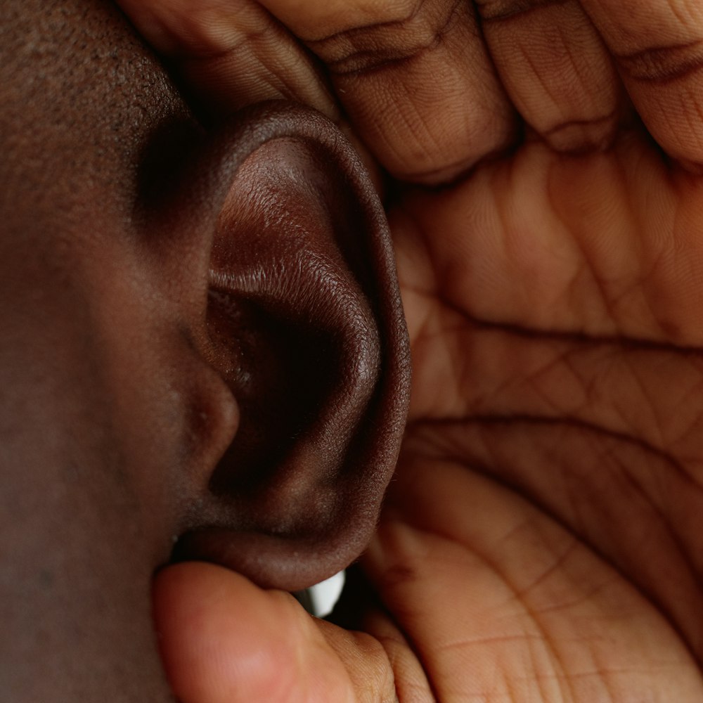 a close up of a person's hand holding a fake ear