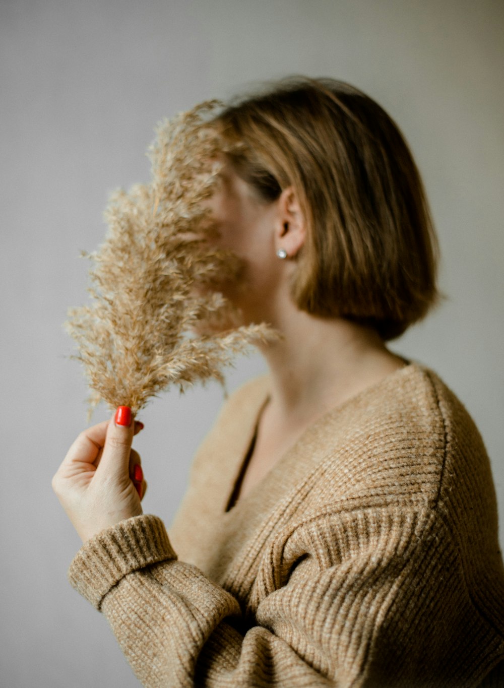 a woman holding a dried plant up to her face
