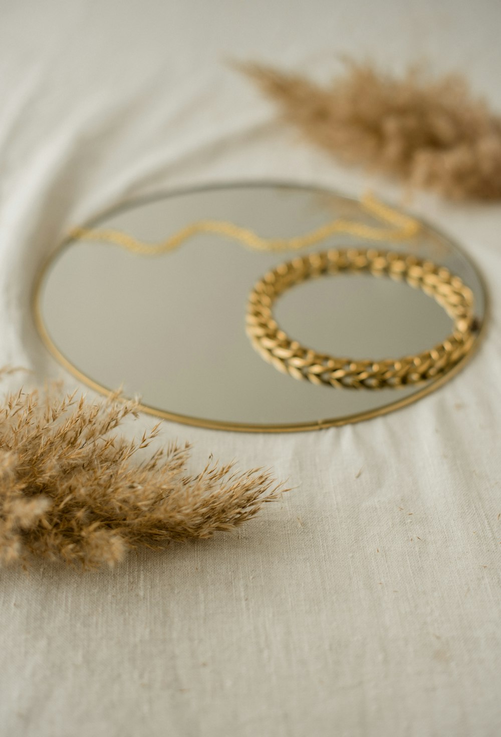 a mirror sitting on top of a table next to dried grass