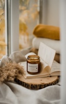 An inviting setup of earthy-toned notebooks and soft amber-hued candles on a sand-colored table.