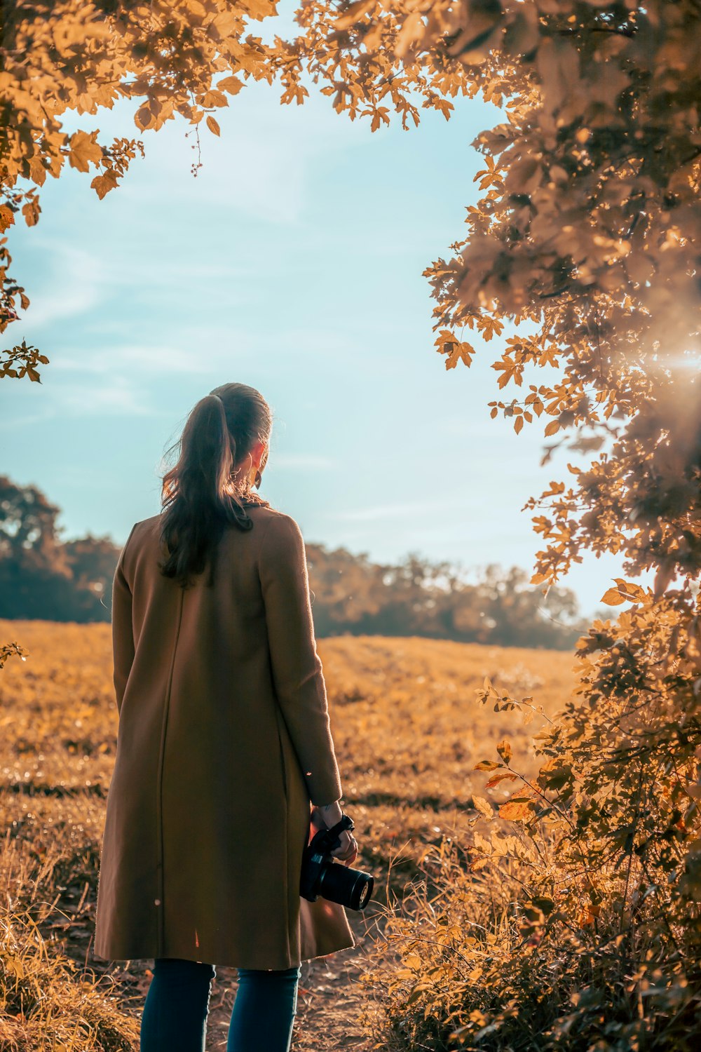 a woman in a coat is walking through a field