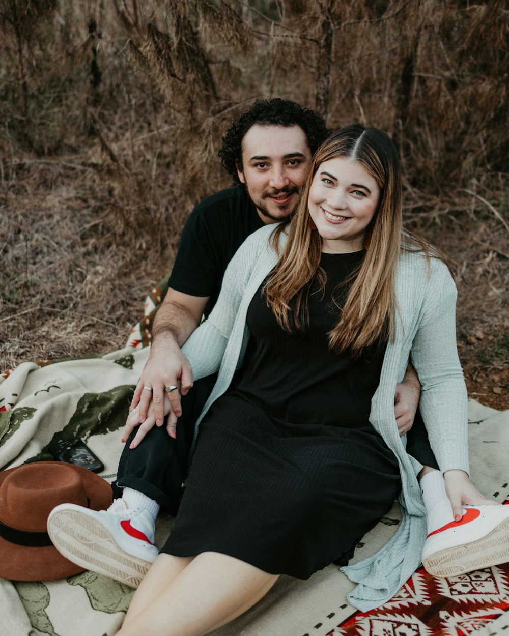 a man and woman sitting on top of a blanket