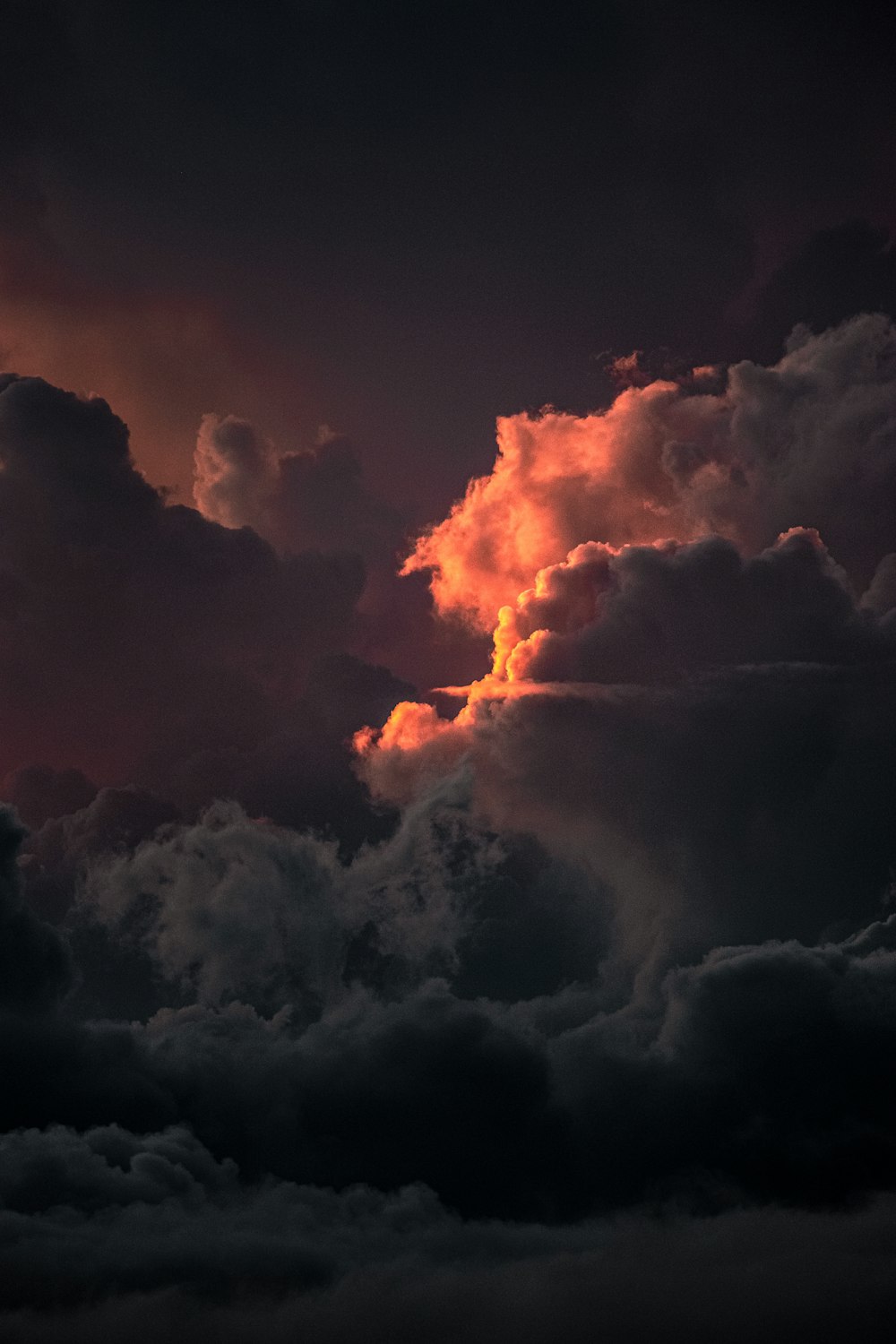 a plane flying through a cloudy sky at sunset