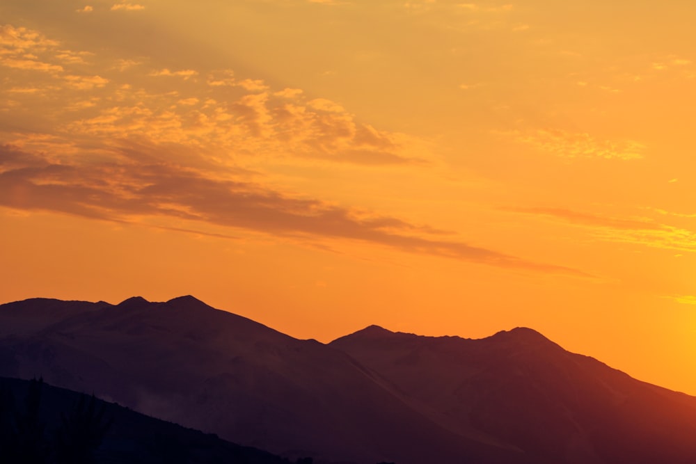 a plane flying over a mountain range at sunset