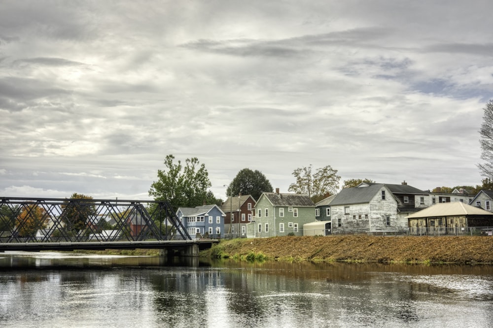 a bridge over a body of water with houses in the background