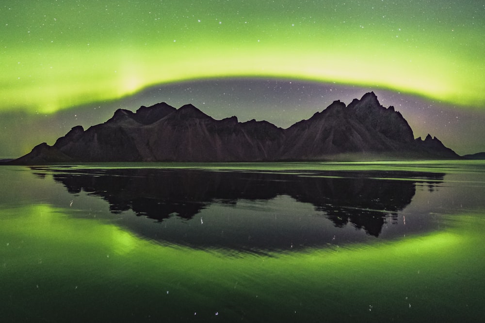 a green and purple aurora over a mountain range